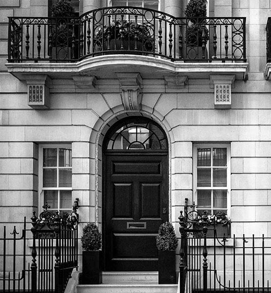 Stone exterior and large arching doorway of a private property in London which is managed by The London Management Company.